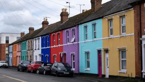 Getty Images A row of colourful houses in Gloucester, with a row of cars in front of them.
