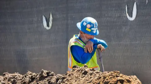 Getty Images Un trabajador de la construcción se toma un breve descanso mientras cava una zanja con una pala en medio de una ola de calor en Irvine el jueves 5 de septiembre de 2024