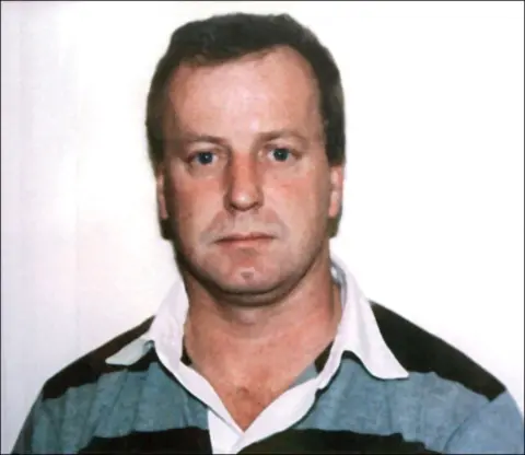 Getty Images Stuart Morgan has short, dark hair and is wearing a grey and black rugby shirt with a white collar