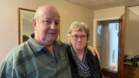 An elderly couple standing hand in hand