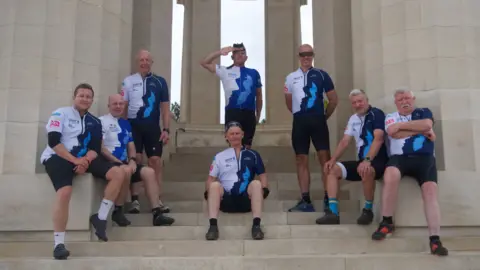 Eight men stood at the front of an American war memorial in France