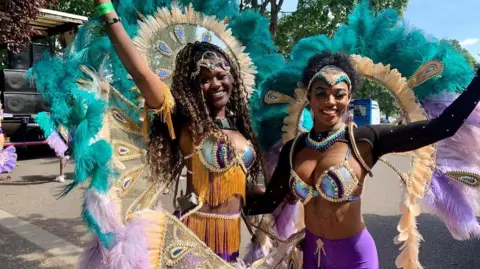 Two women dressed in brightly coloured costumes. 