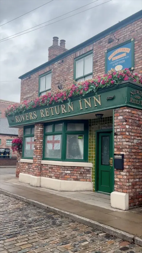 Rovers Return Inn pub from Coronation Street. It it a full brick building with a green sign.