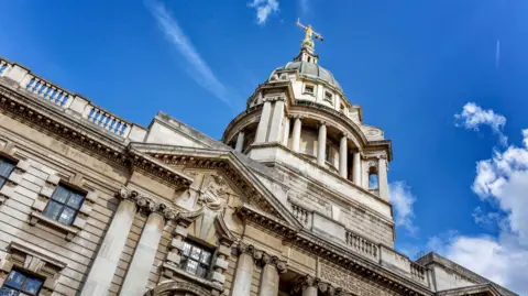 Getty image of the Old Bailey building, pictured from street level against a blue sky background
