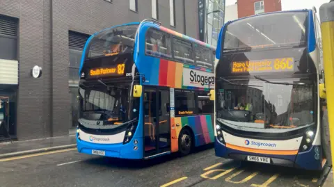 BBC Two double-decker Stagecoach buses with blue liveries line up at a bus station on a street in Liverpool 