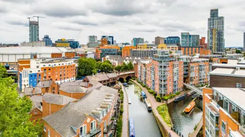 Getty Images The Birmingham Canal Old Line in the city centre has barges on the water and apartment blocks and other buildings surrounding the waterways.