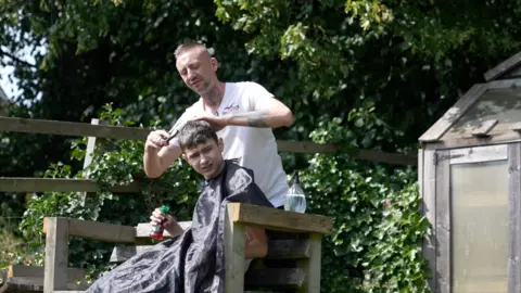 Jonathan Paton cutting an autistic client's hair outside