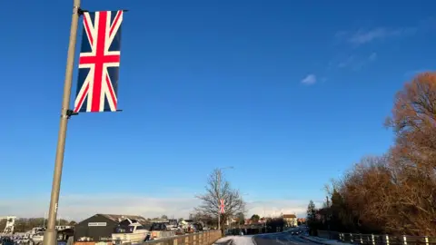A union jack flag on a lamp post with snowy scenes in the background.