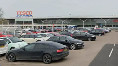 Google Cars parked in a Tesco car park. The entrance to the store is in the background.