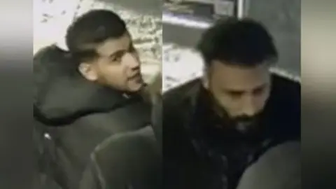 A CCTV image composite showing two men. The one of the left has short dark hair and stubble and is wearing a black puffer jacket with a hood. He is looking over his right shoulder. The man on the right has dark hair, cropped at the sides, and a black beard. He is looking down and is wearing dark clothing