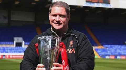 Liverpool Women manager Matt Beard holds the Women's Championship trophy ahead of kick-off between Liverpool and Sheffield United in 2022
