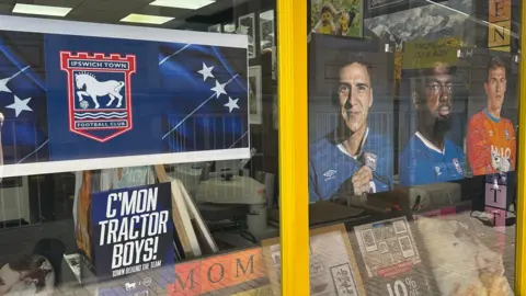 Ben Parker/BBC A shop window with posters supporting Ipswich Town.