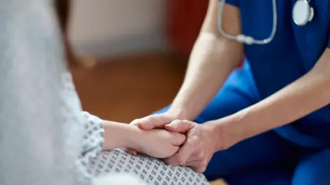 A close up of a nurse's hand holding that of a patient