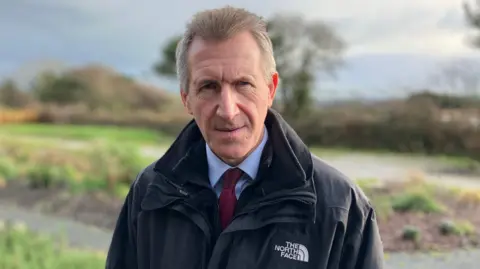 A man with grey hair looks sternly at the camera 
