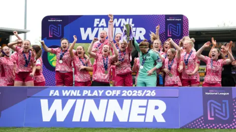 Getty Images Norwich City women's team celebrating being promoted on Sunday at Pirelli Stadium in Burton-on-Trent. The team are all celebrating and have medals round their necks.