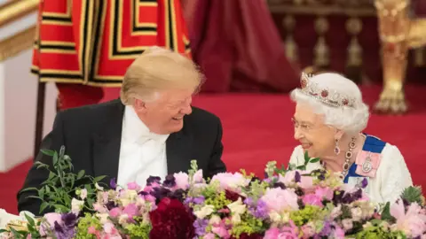 PA Media Donald Trump laughing with Queen Elizabeth II at a state banquet. 