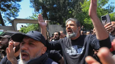 A crowd of Druze men gesture with their hands in the air
