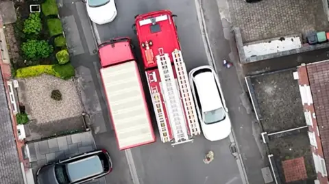 Overhead shot of fire engine squeezing past vehicles