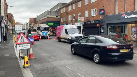 Roadworks in Bridgwater. A car is pictured waiting at traffic lights and a sign indicates there is single file trafic.