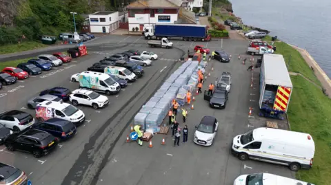 Ben Birchall/PA Media A drone photo showing people collecting bottles of water in Brixham