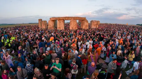 Getty Images Large groups of people stood by big stones
