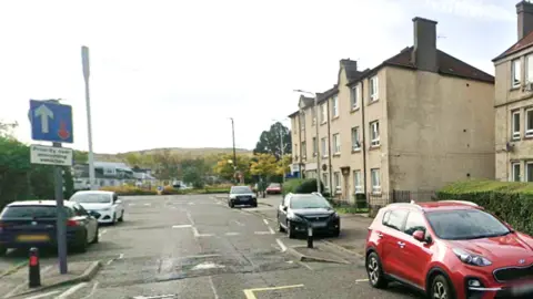 several cars parked on either side of a street of flats