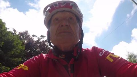 Image of Tony Newton in his cycling clothes and helmet taking from his bike's handlebars
