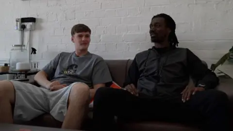 Jack and Dom sat together on a sofa, both wearing casual clothing, talking about their vision for the documentary.