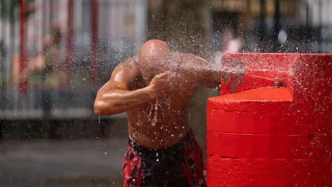 A person cools off in a water fountain in New York City in July 2024