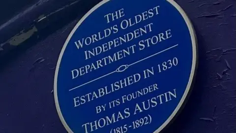 A blue plague that hangs outside the former Austins department store in Derry denoting the year it opened and that it is the 'worlds oldest independent department store'