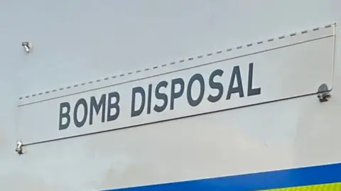 The words "BOMB DISPOSAL" on the side of a police vehicle.