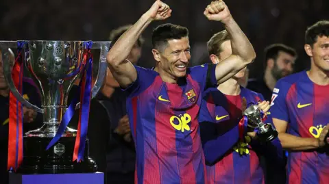 Robert Lewandowski celebrating next to the Liga trophy.