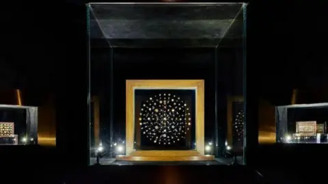 The photo shows jewels linked to the Buddha's remains displayed behind a glass casing. These are considered among the most extraordinary archaeological finds of all time