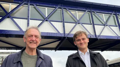 BBC/RICHARD EDWARDS Terry French, from Selby and District Rail Users' Group, and Selby's Labour MP Keir Mather, in front of the restored and strengthened Grade II listed footbridge at Selby Railway Station
