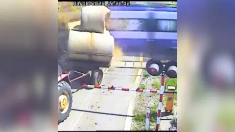 Train crashing into trailer carrying bales of straw