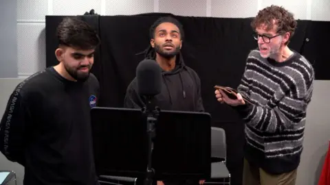 BBC Young Bradford actors Armaan Ali and Solomon Gordon are pictured with Emmerdale star Mark Charnock in a radio studio, in the midst of recording the play.