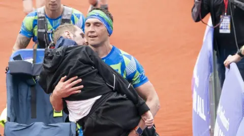 PA Media Rob Burrow is carried over the 2023 marathon finish line by his friend and former team-mate Kevin Sinfield