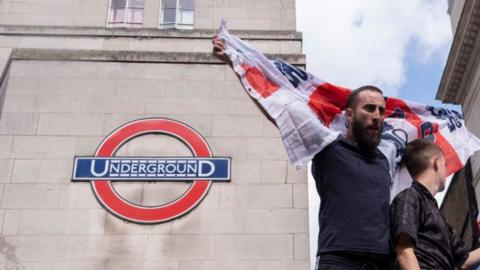 England fan waving flag in front of Underground sign