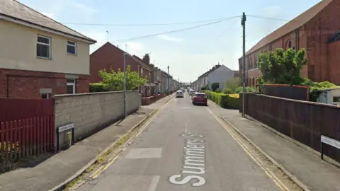 Google Maps Summers Street, Swindon on a sunny day with blue sky. A straight road with residential, terraced homes down either side. Cars parked down the street.