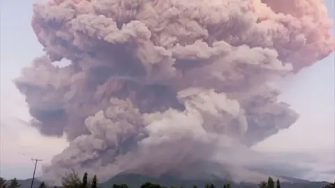 Huge plumes of purple and pink-hued smoke are seen from above Mount Lewotobi