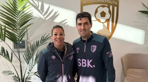 Evie Pardy Evie Pardy alongside Andoni Iraola both in an AFC Bournemouth building wearing AFC Bournemouth tracksuits.
