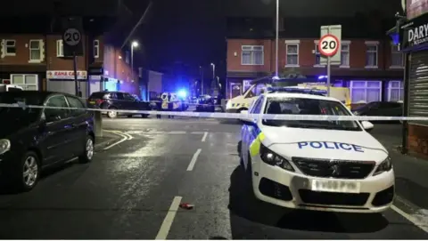 A police cordon is in place blocking off the street with a number of police vehicles present.