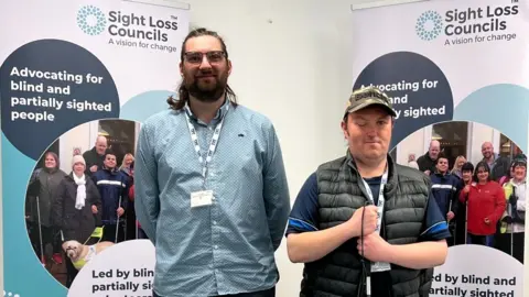 Tyne and Wear Sight Loss Council Tyne and Wear Sight Loss Council volunteers Jack Moffat and Matty Bolam standing in front of two banners