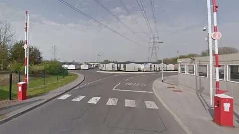 Google The main entrance gate of Swift caravans with red and white barriers and a number of holiday homes in the background