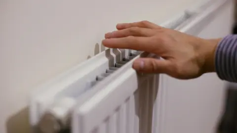 A person checks the heat coming out of a radiator