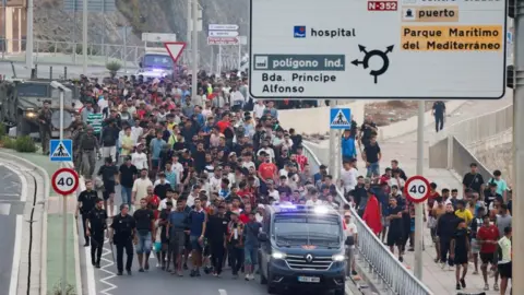Police officers and Spanish soldiers escort a big group of migrants to the border to take them out of Spain,