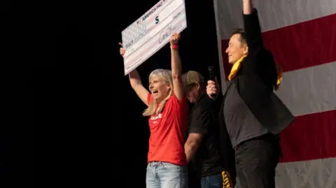 Getty Images Elon Musk handing a woman a giant cheque on 21 October