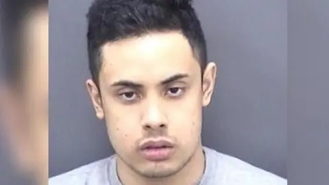 Police custody photo of Nasen Saadi. He has short black hair, dark eyes and is looking to camera