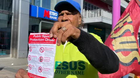 Rev Don Balkaran holding a copy of the new Public Space Protection Order in Leicester city centre