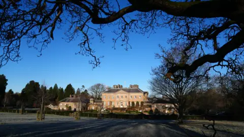 PA Media A view of Dumfries House taken from underneath a tree, looking over a field on a frosty day. 